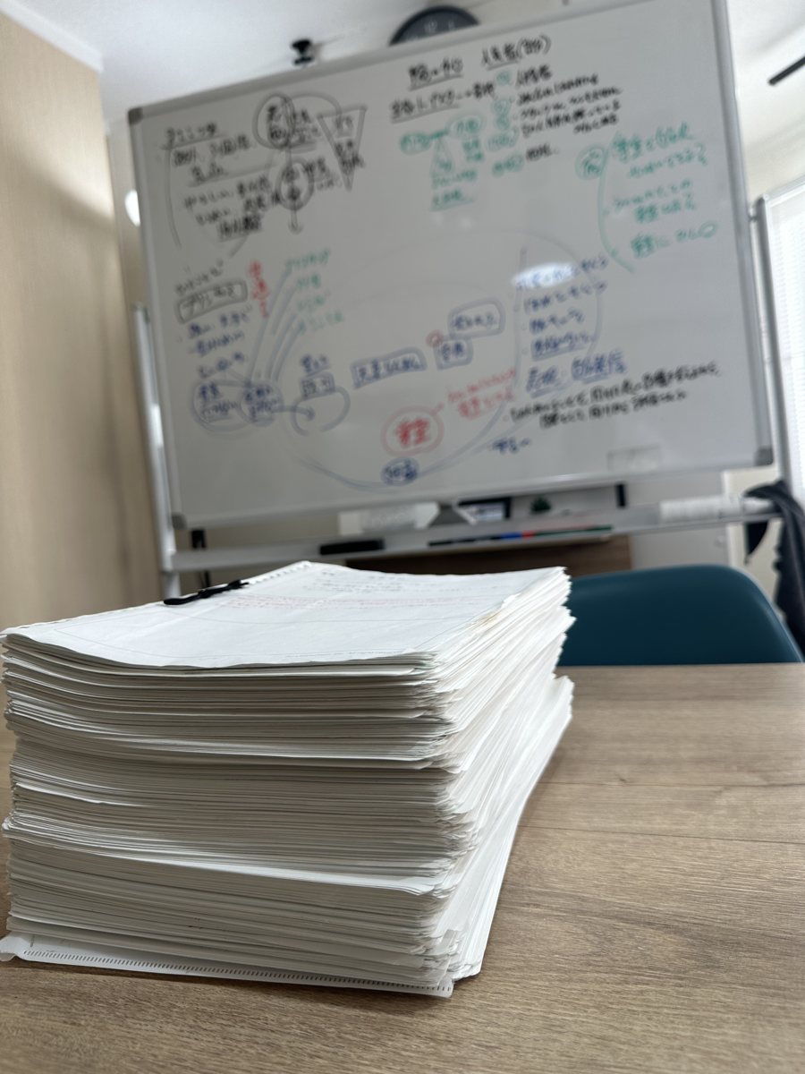 机の上に積み上げられた、書き終えた自分史の紙の束