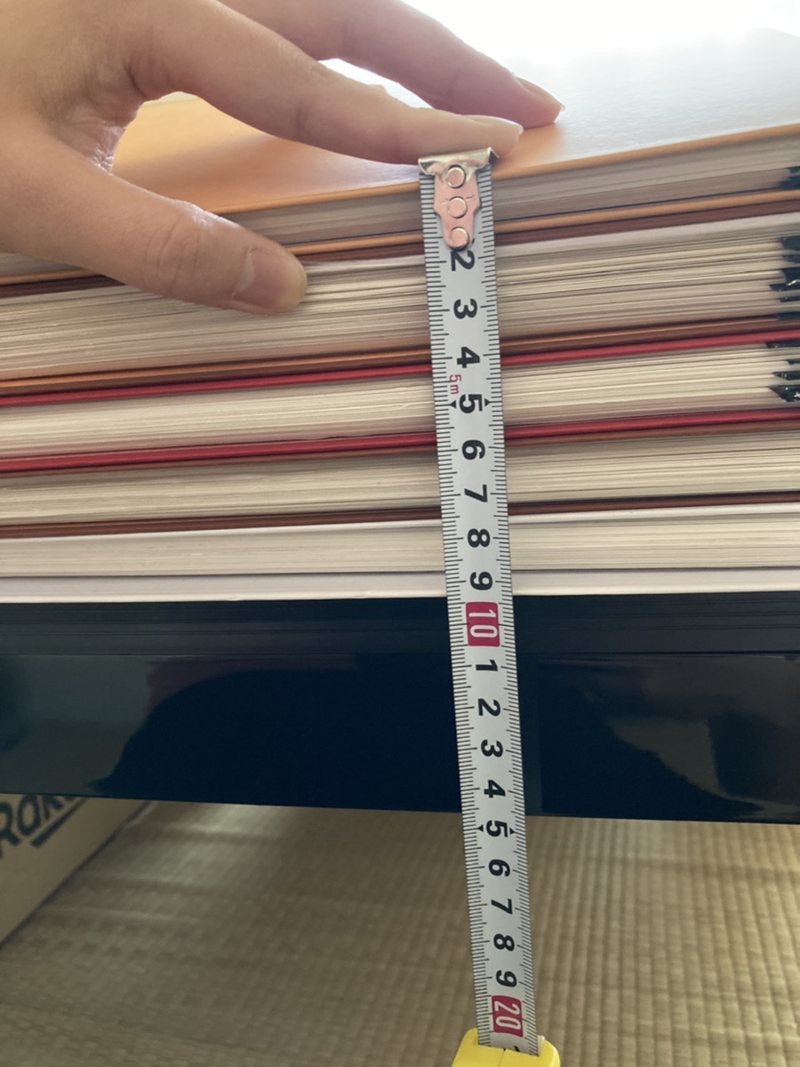 書き上がった自分史の紙の束の厚みを、メジャーで測っている様子